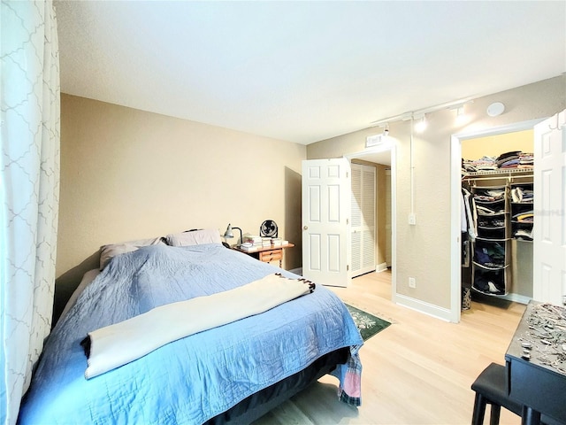 bedroom with light wood finished floors, a walk in closet, and a closet