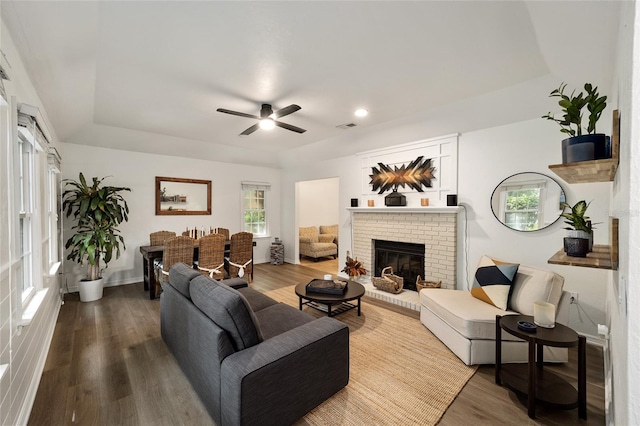 4511 SW 83rd Dr, Gainesville, FL 32608 - living room with a tray ceiling, ceiling fan, a brick fireplace, dark wood finished floors, and recessed lighting