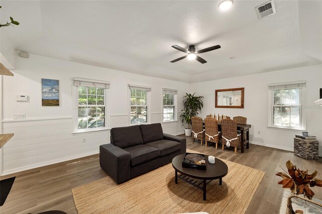 4511 SW 83rd Dr, Gainesville, FL 32608 - living area with a tray ceiling, wood finished floors, ceiling fan, baseboards, and wainscoting
