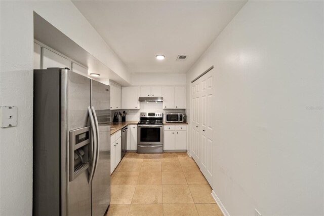 4511 SW 83rd Dr, Gainesville, FL 32608 - kitchen with stainless steel appliances, under cabinet range hood, white cabinetry, light tile patterned floors, and dark countertops