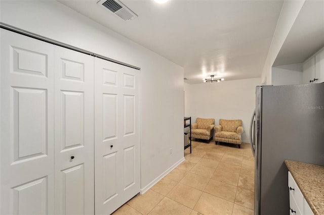 4511 SW 83rd Dr, Gainesville, FL 32608 - kitchen with freestanding refrigerator, light tile patterned floors, light stone countertops, open floor plan, and white cabinetry