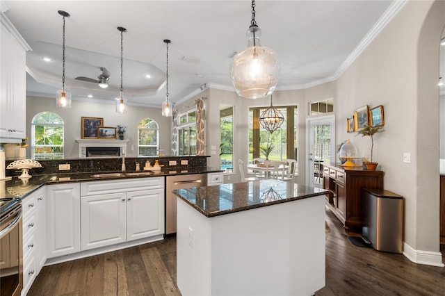 kitchen with dark wood-style flooring, appliances with stainless steel finishes, ornamental molding, and a sink