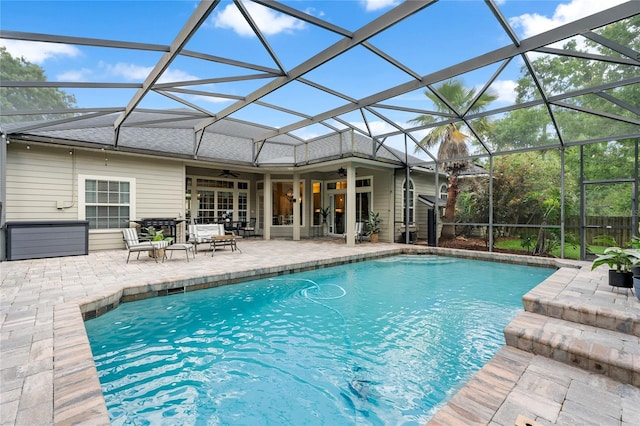 pool with glass enclosure, a ceiling fan, and a patio area