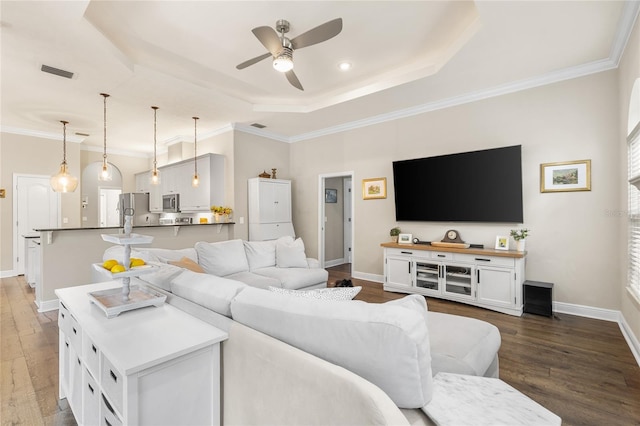 living room with visible vents, baseboards, dark wood-type flooring, a raised ceiling, and a ceiling fan