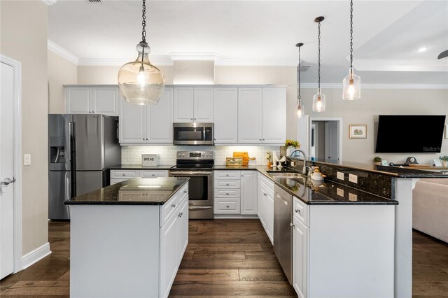kitchen featuring decorative backsplash, a peninsula, white cabinets, a sink, and appliances with stainless steel finishes