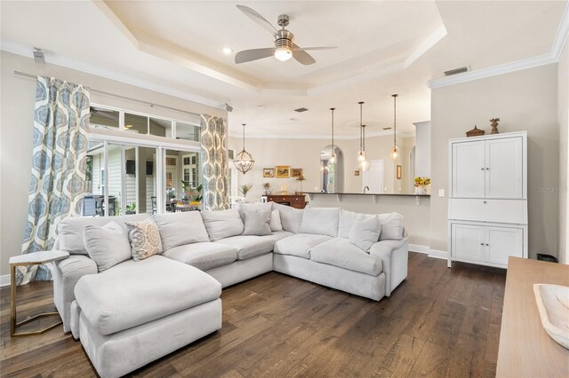 living area featuring dark wood-style flooring, ceiling fan, a raised ceiling, baseboards, and visible vents
