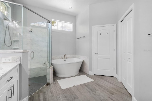 bathroom featuring vanity, wood finished floors, a soaking tub, and a stall shower