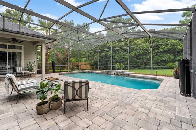 pool featuring glass enclosure, ceiling fan, and a patio area