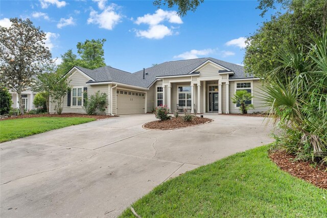 ranch-style house with driveway, a shingled roof, a front yard, and a garage