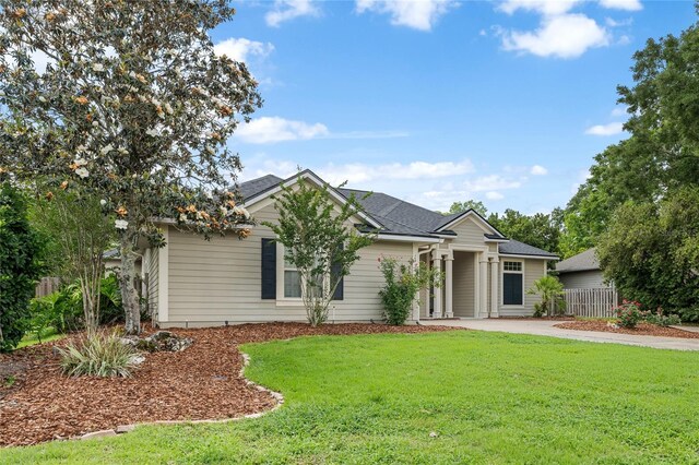 ranch-style home with a front lawn, fence, and concrete driveway