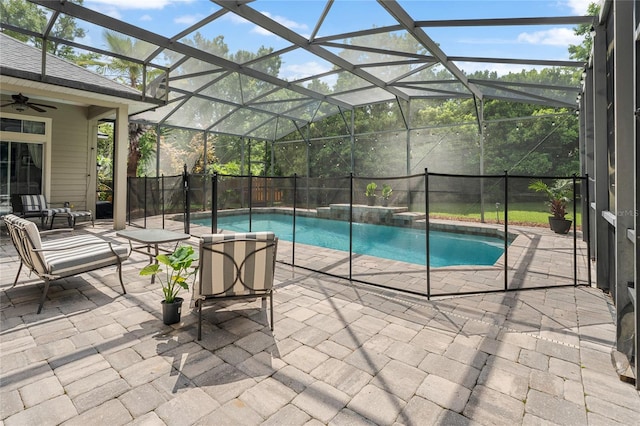view of swimming pool featuring a fenced in pool, a fenced backyard, a patio area, a ceiling fan, and glass enclosure