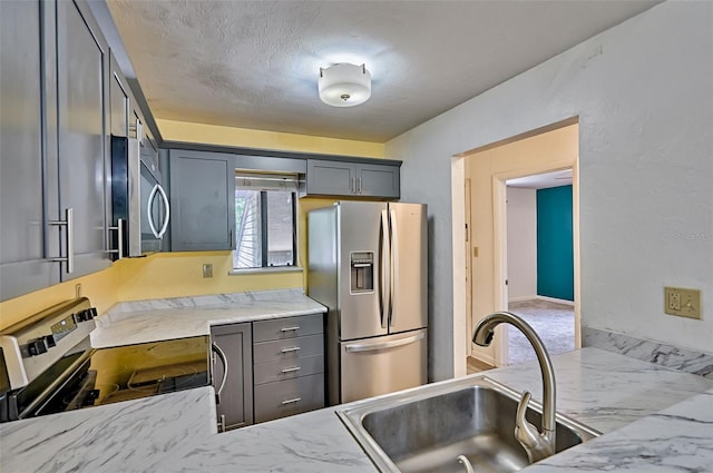 111 SE 16th Ave Unit O304, Gainesville, FL 32601 - kitchen with stainless steel appliances, gray cabinetry, light stone counters, and a textured ceiling