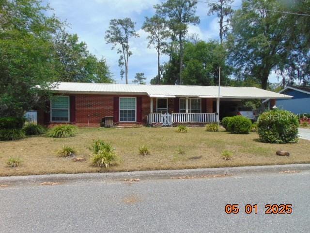 single story home with a porch, a front lawn, and an attached carport
