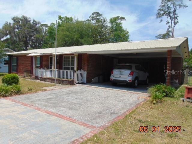 single story home with a carport, driveway, and covered porch