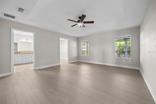 empty room with ceiling fan, visible vents, baseboards, and light wood-type flooring