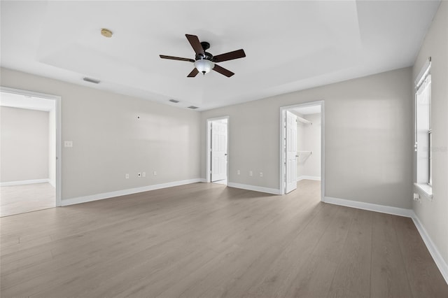 spare room with plenty of natural light, a ceiling fan, wood finished floors, and visible vents