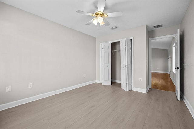 unfurnished bedroom with baseboards, a closet, wood finished floors, and visible vents