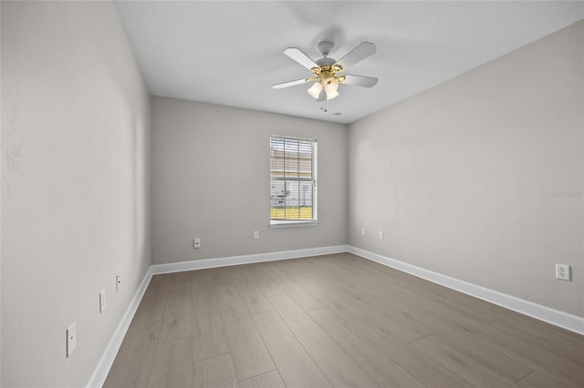 empty room featuring a ceiling fan, baseboards, and wood finished floors