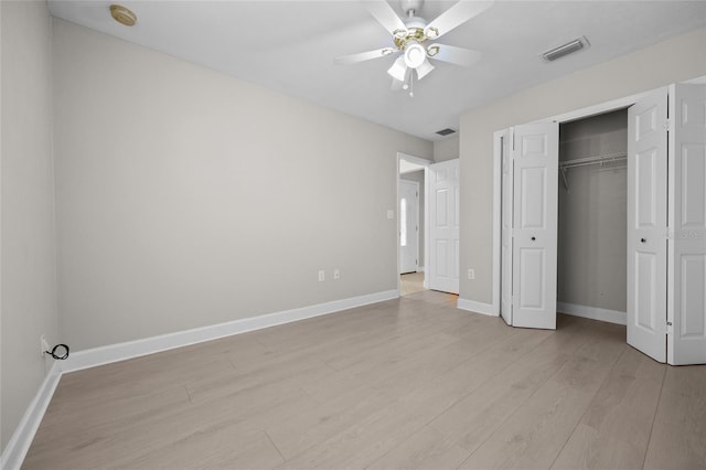 unfurnished bedroom featuring ceiling fan, light wood-style flooring, baseboards, visible vents, and a closet