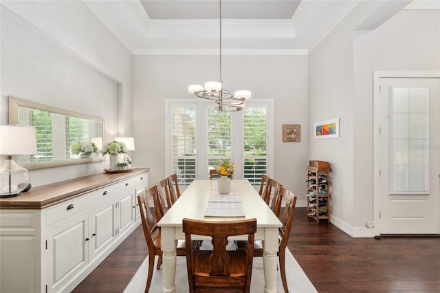 dining space featuring crown molding, an inviting chandelier, baseboards, dark wood-type flooring, and a tray ceiling