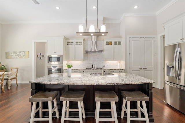 kitchen with glass insert cabinets, a kitchen breakfast bar, wall chimney exhaust hood, tasteful backsplash, and appliances with stainless steel finishes