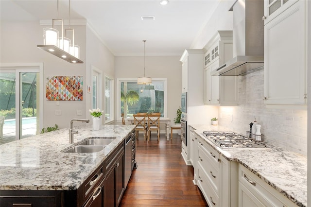 kitchen featuring decorative backsplash, dark brown cabinetry, appliances with stainless steel finishes, a sink, and wall chimney exhaust hood