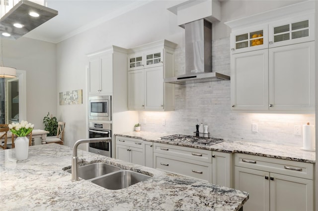 kitchen with wall chimney range hood, a sink, stainless steel appliances, white cabinetry, and decorative backsplash