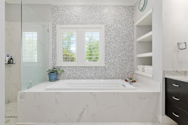full bathroom featuring vanity, a garden tub, and tile walls