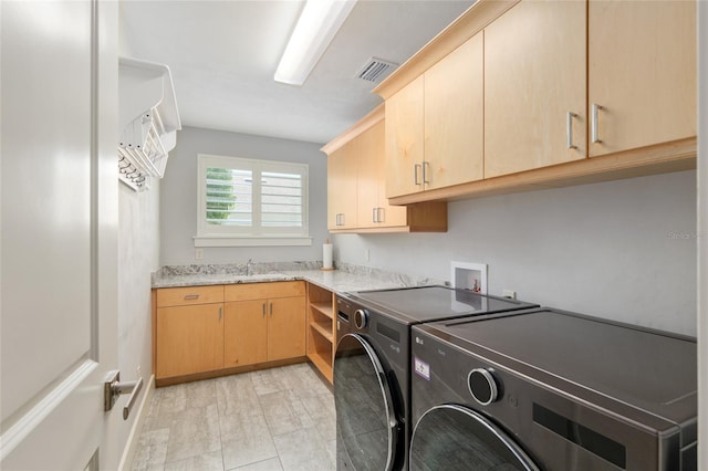 washroom featuring cabinet space, visible vents, washing machine and dryer, and a sink