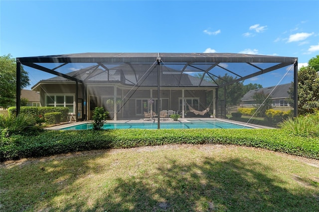 rear view of property with a lawn, an outdoor pool, and a lanai