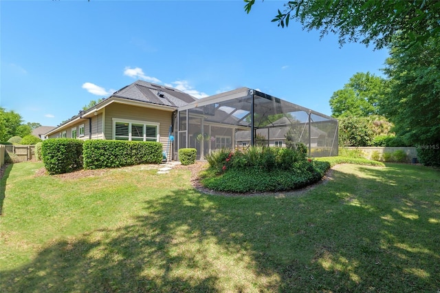 rear view of property with fence, a lanai, and a lawn