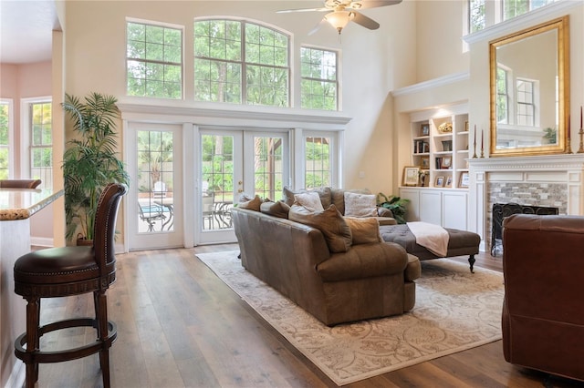 4515 SW 97th Ter, Gainesville, FL 32608 - living room featuring a towering ceiling, a ceiling fan, plenty of natural light, a tiled fireplace, and hardwood / wood-style flooring
