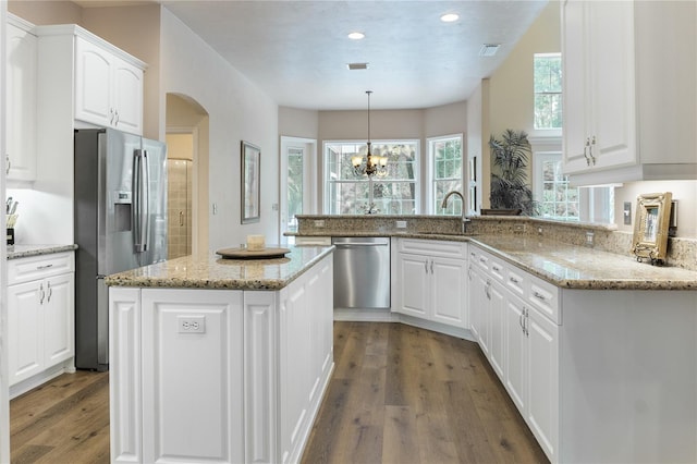 4515 SW 97th Ter, Gainesville, FL 32608 - kitchen with stainless steel appliances, a sink, wood finished floors, arched walkways, and white cabinetry
