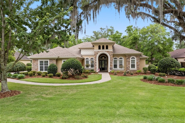 mediterranean / spanish house with stone siding, stucco siding, and a front yard