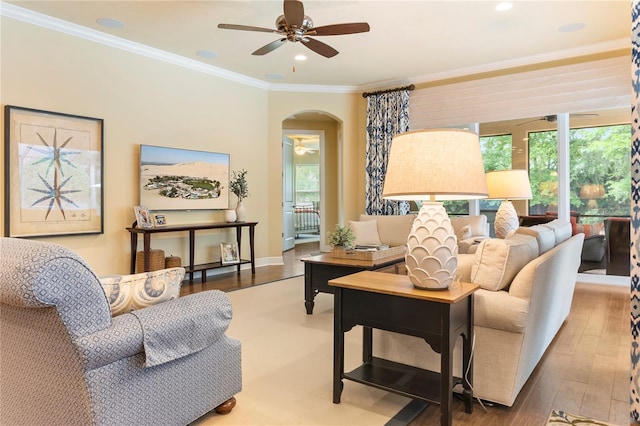 living area with a ceiling fan, arched walkways, wood-type flooring, ornamental molding, and recessed lighting