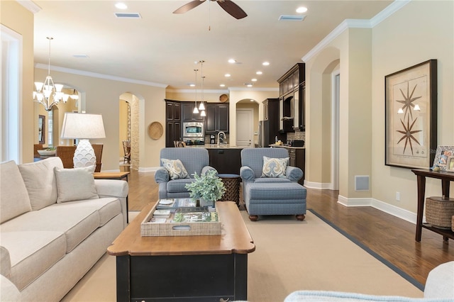 living room featuring arched walkways, a ceiling fan, wood finished floors, baseboards, and ornamental molding