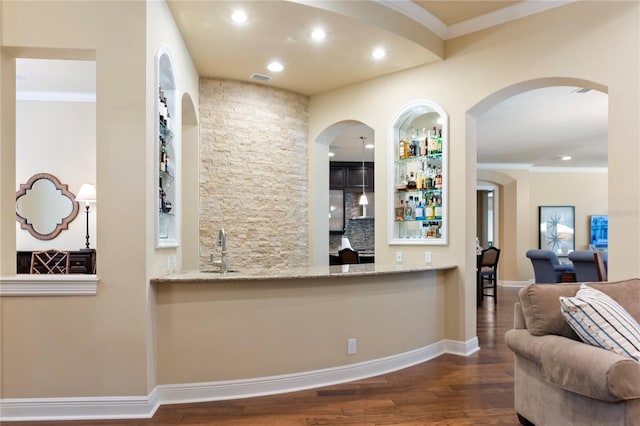indoor wet bar with wood finished floors, recessed lighting, ornamental molding, baseboards, and arched walkways