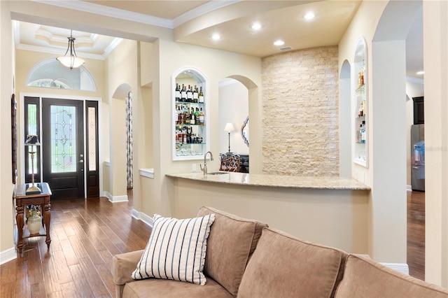 foyer entrance featuring bar with sink, wood finished floors, ornamental molding, recessed lighting, and baseboards