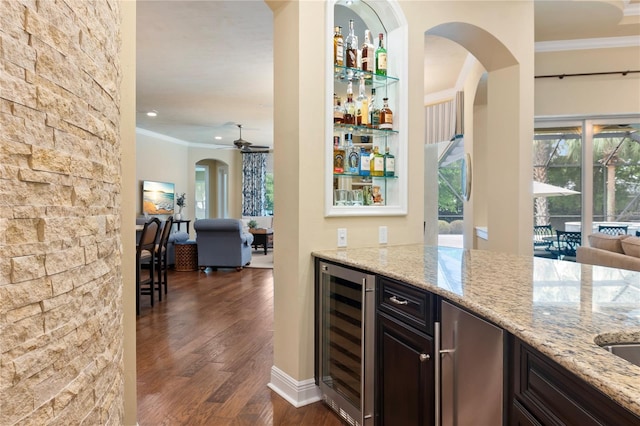 indoor dry bar with wine cooler, ornamental molding, dark wood-style flooring, healthy amount of natural light, and ceiling fan