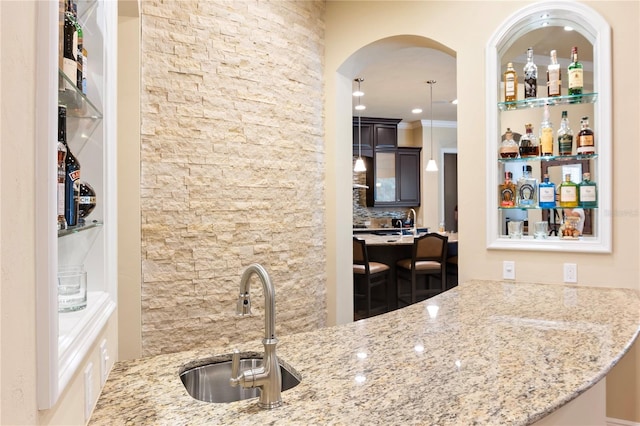 bar featuring a sink, arched walkways, and decorative backsplash