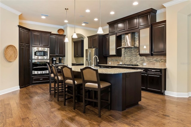 kitchen featuring wall chimney range hood, appliances with stainless steel finishes, arched walkways, tasteful backsplash, and baseboards