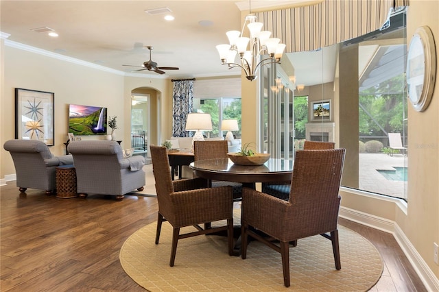 dining room featuring arched walkways, wood finished floors, crown molding, baseboards, and ceiling fan