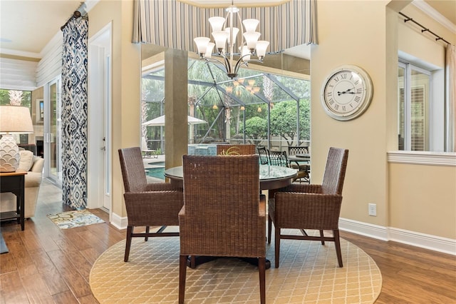 dining area featuring baseboards, wood finished floors, a chandelier, and ornamental molding