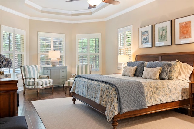 bedroom with a tray ceiling, ornamental molding, wood finished floors, and a ceiling fan