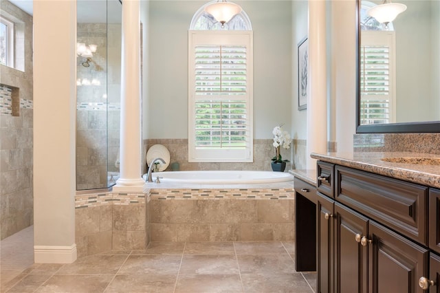 bathroom featuring a garden tub, ornate columns, vanity, and walk in shower