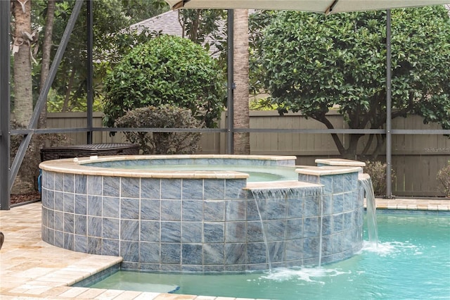 view of pool with fence and a pool with connected hot tub