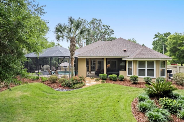 rear view of house with an outdoor pool, roof with shingles, a lawn, a lanai, and stucco siding