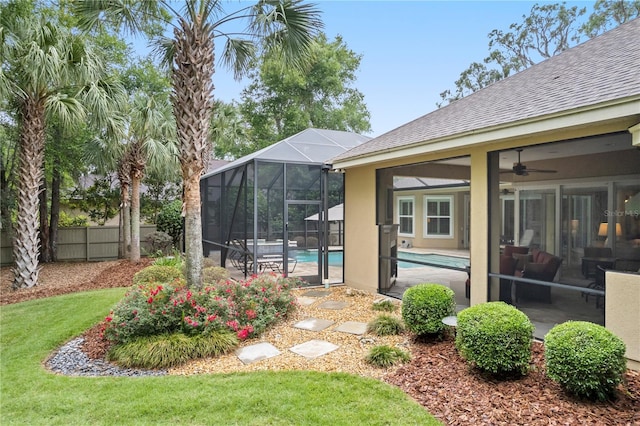 view of yard featuring an outdoor pool, ceiling fan, a patio area, and a lanai