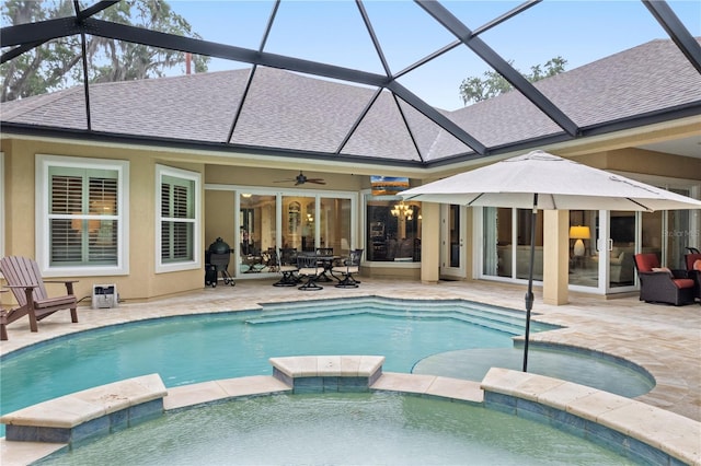 view of swimming pool featuring a pool with connected hot tub, a patio, and glass enclosure