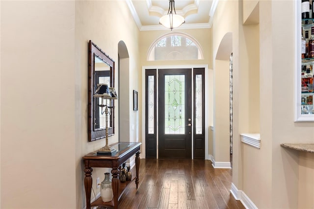 entryway with arched walkways, ornamental molding, dark wood-style flooring, baseboards, and a towering ceiling